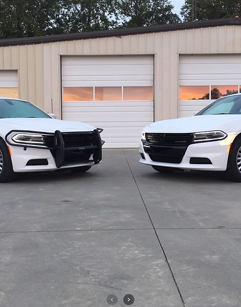 Two white police cruisers in front of a building