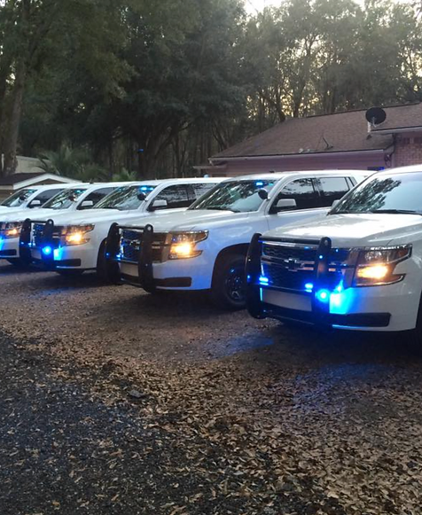 Row of police SUVs parked side by side with lights on