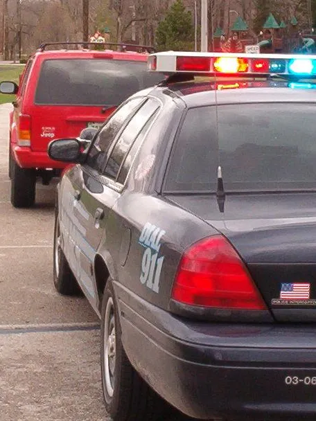Police interceptor with lights flashing behind red Jeep Cherokee
